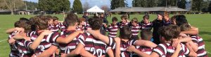 A huddling group of students on an athletic field.