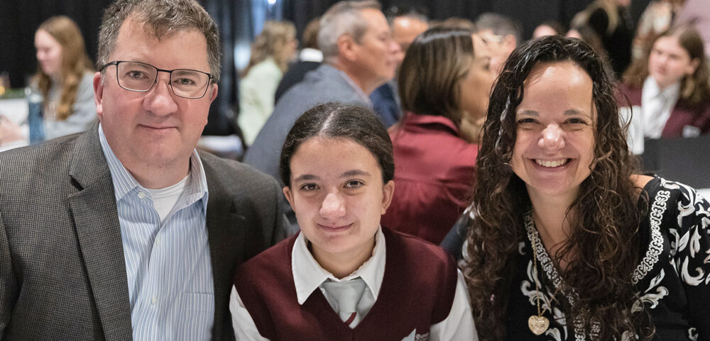 Rundle Academy | A Rundle Academy family smiles in the gymnasium during the Moves Mountains Breakfast | private school calgary