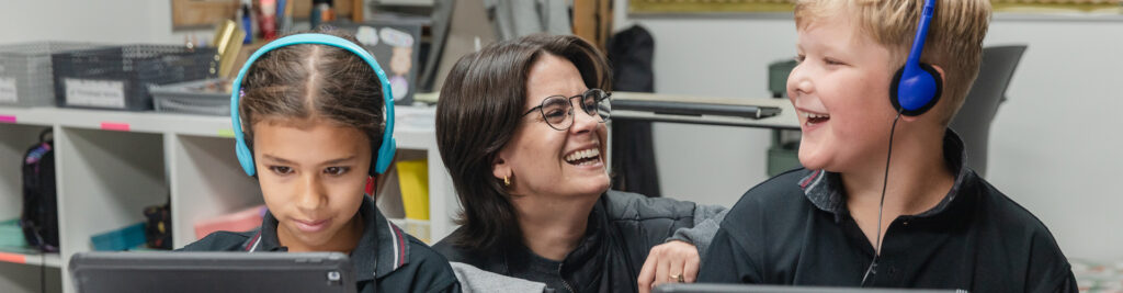 Rundle Academy | a teacher and student smile at each other while the student works on an iPad | private school calgary