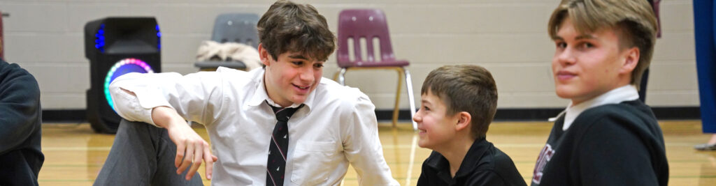 Rundle College | grade 12 and grade 4 student buddies smile in the gymnasium | private school calgary