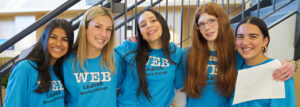 Five student leaders wearing blue WEB Leader t-shirts pose for a photo.